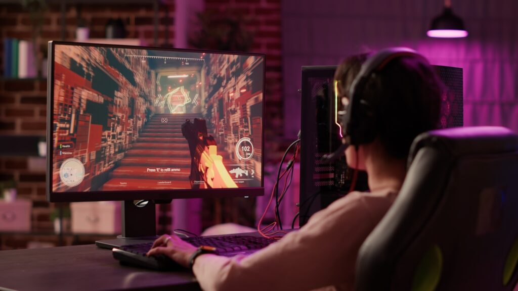 Over shoulder view of gamer girl using pc gaming setup relaxing playing multiplayer online action