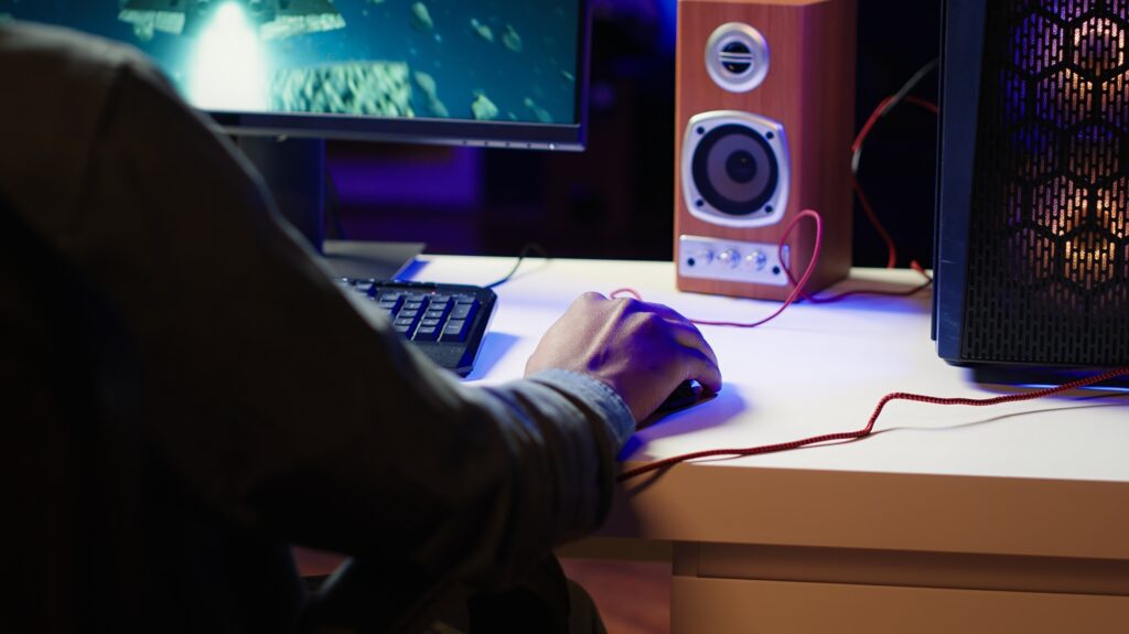 Player using keyboard and mouse to play videogame on gaming PC